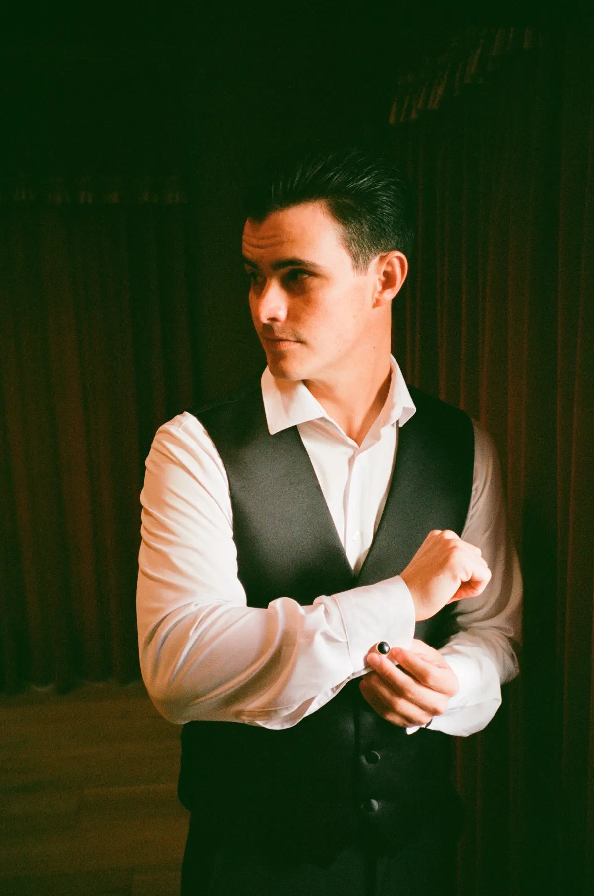 Groom by window — moody warm portrait