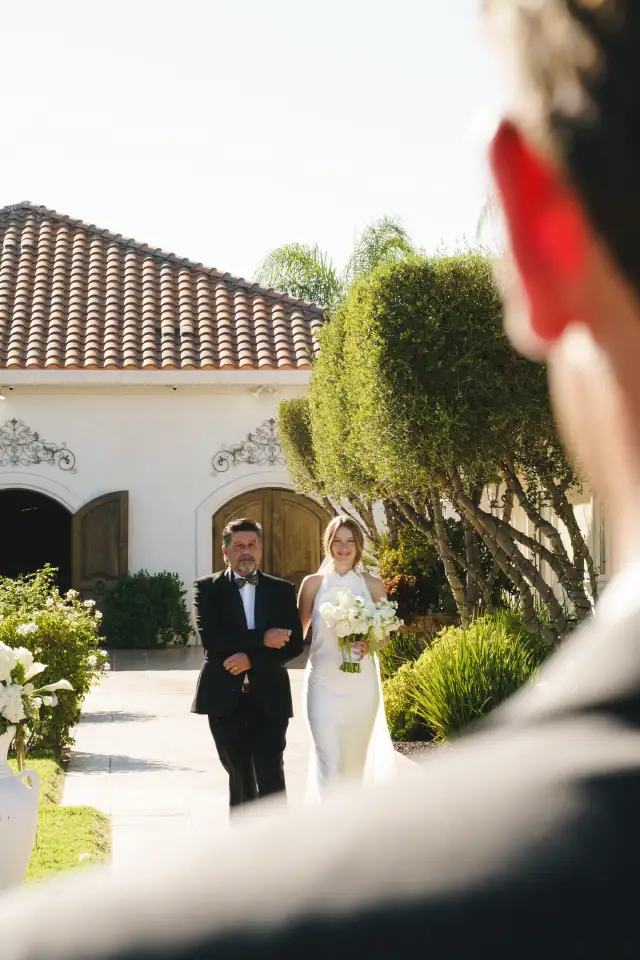 Bride walking toward the outdoor ceremony with her father at Villa de Amore
