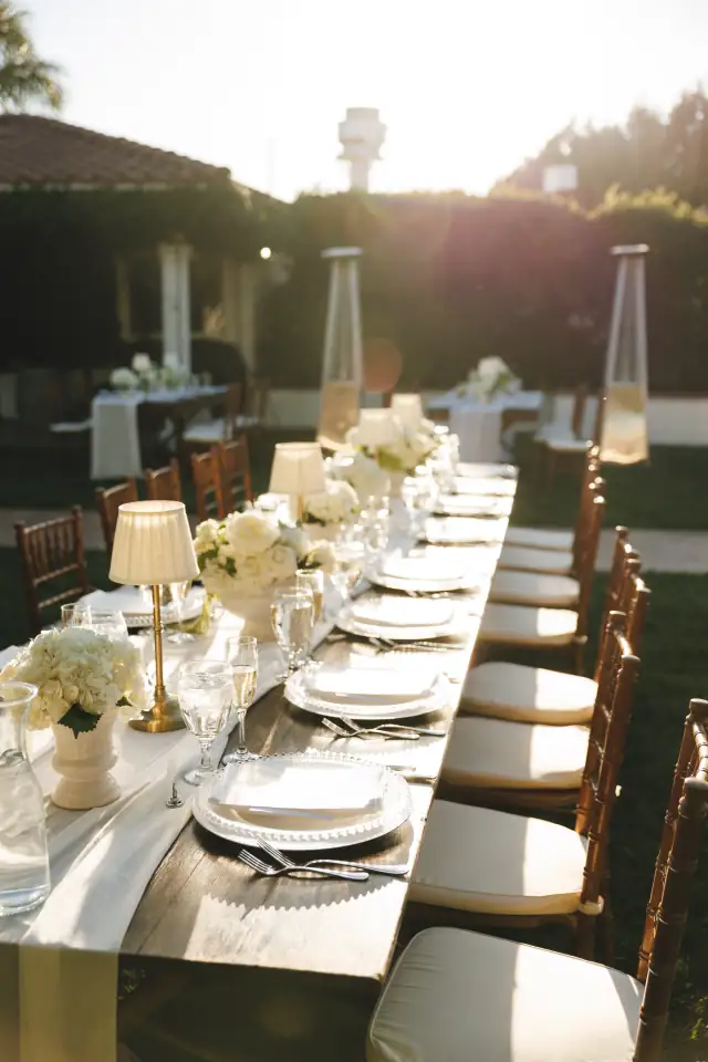 Outdoor wedding reception table set with white flowers at Villa de Amore