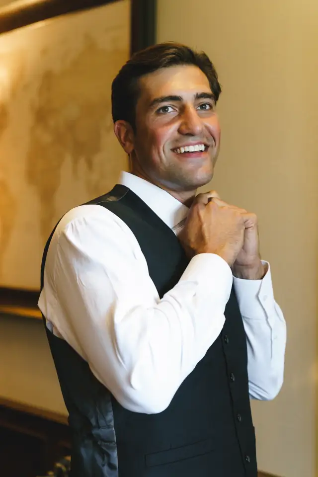 Groom fastening his collar while getting ready at Villa de Amore