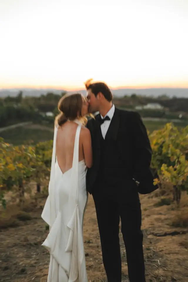 Newlyweds touching foreheads in the vineyard at sunset