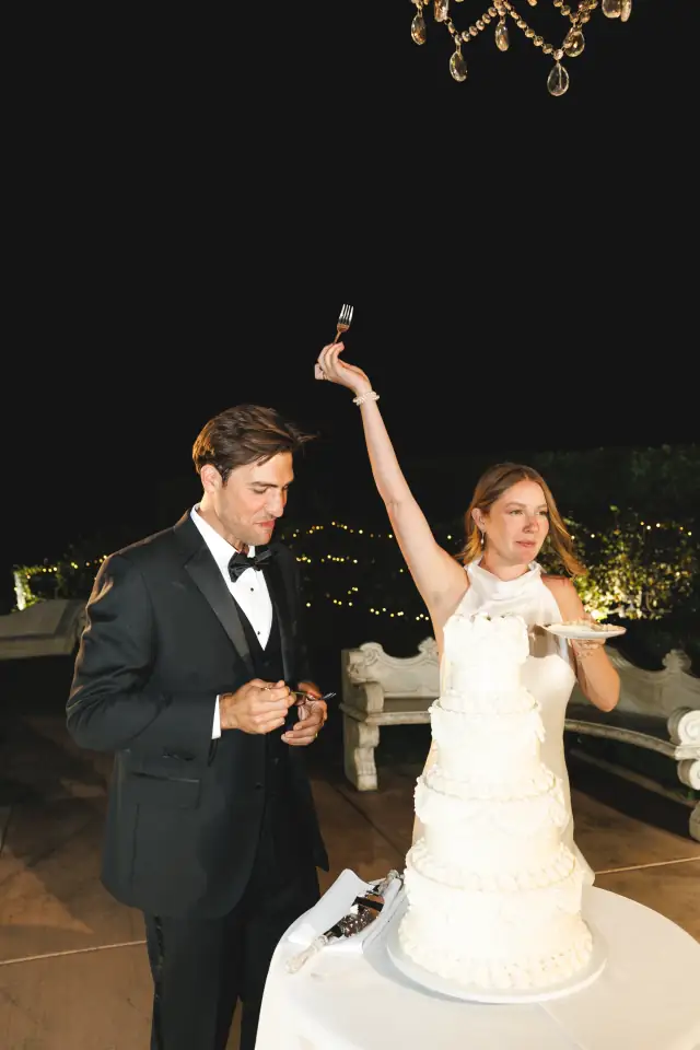 Newlyweds raising their hands after cutting the wedding cake