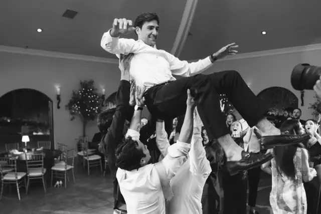 Groom lifted above the dance floor by wedding guests