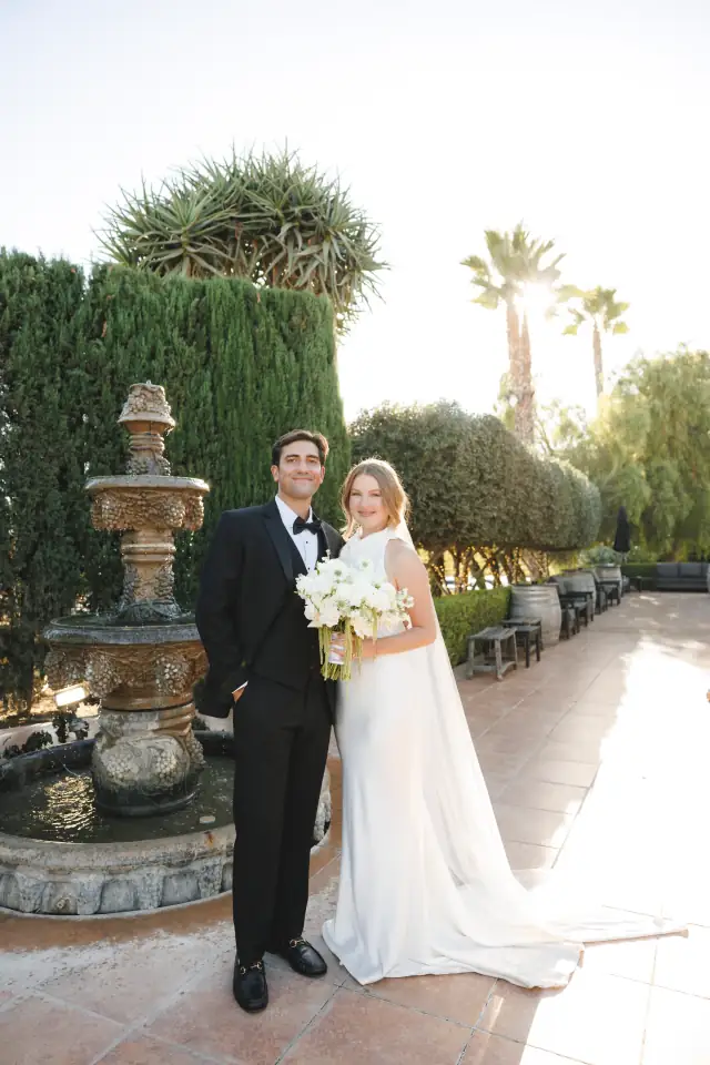 Newlyweds posing beside a courtyard fountain at Villa de Amore