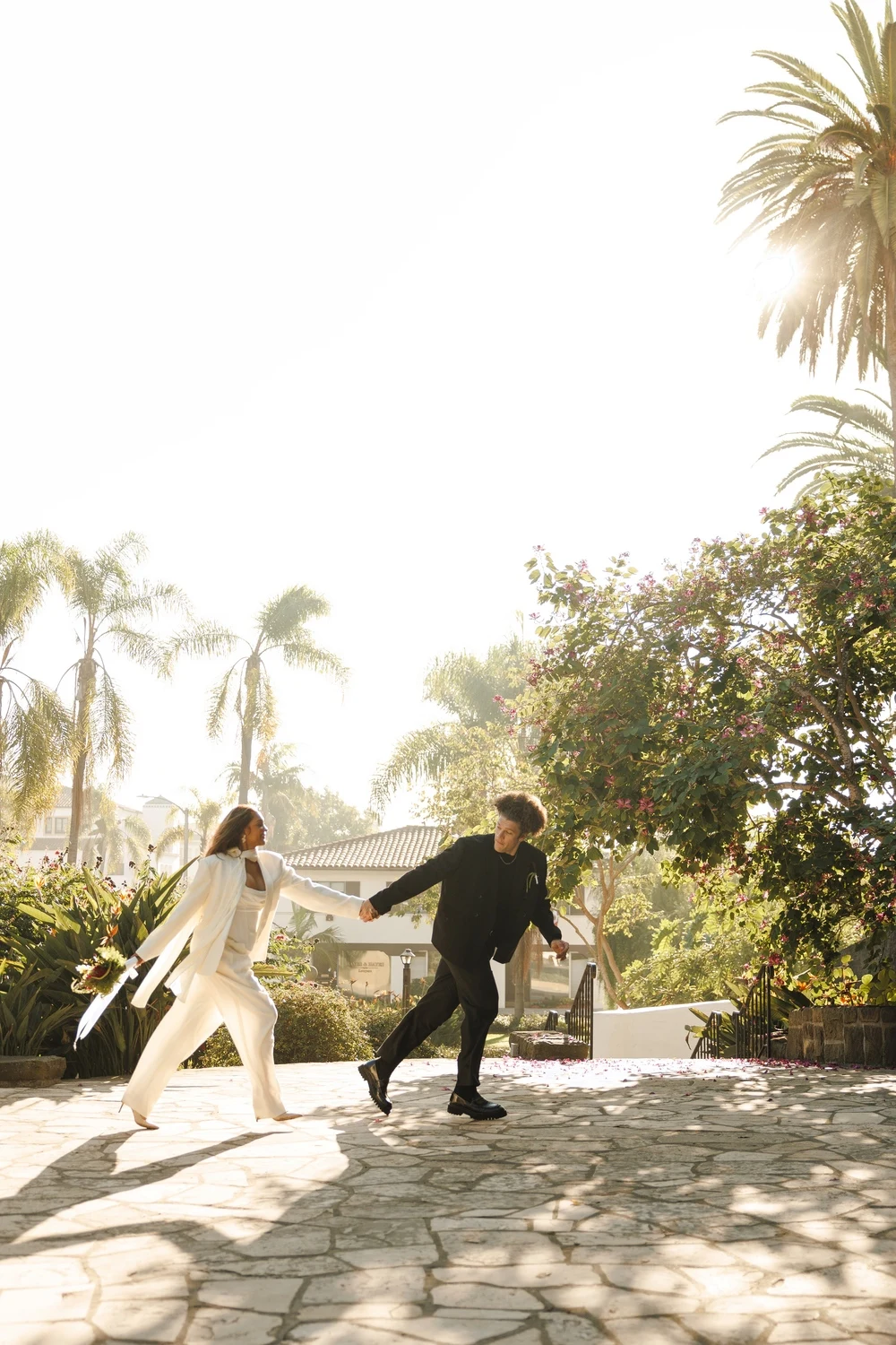 Newlyweds running hand in hand through a sunlit garden