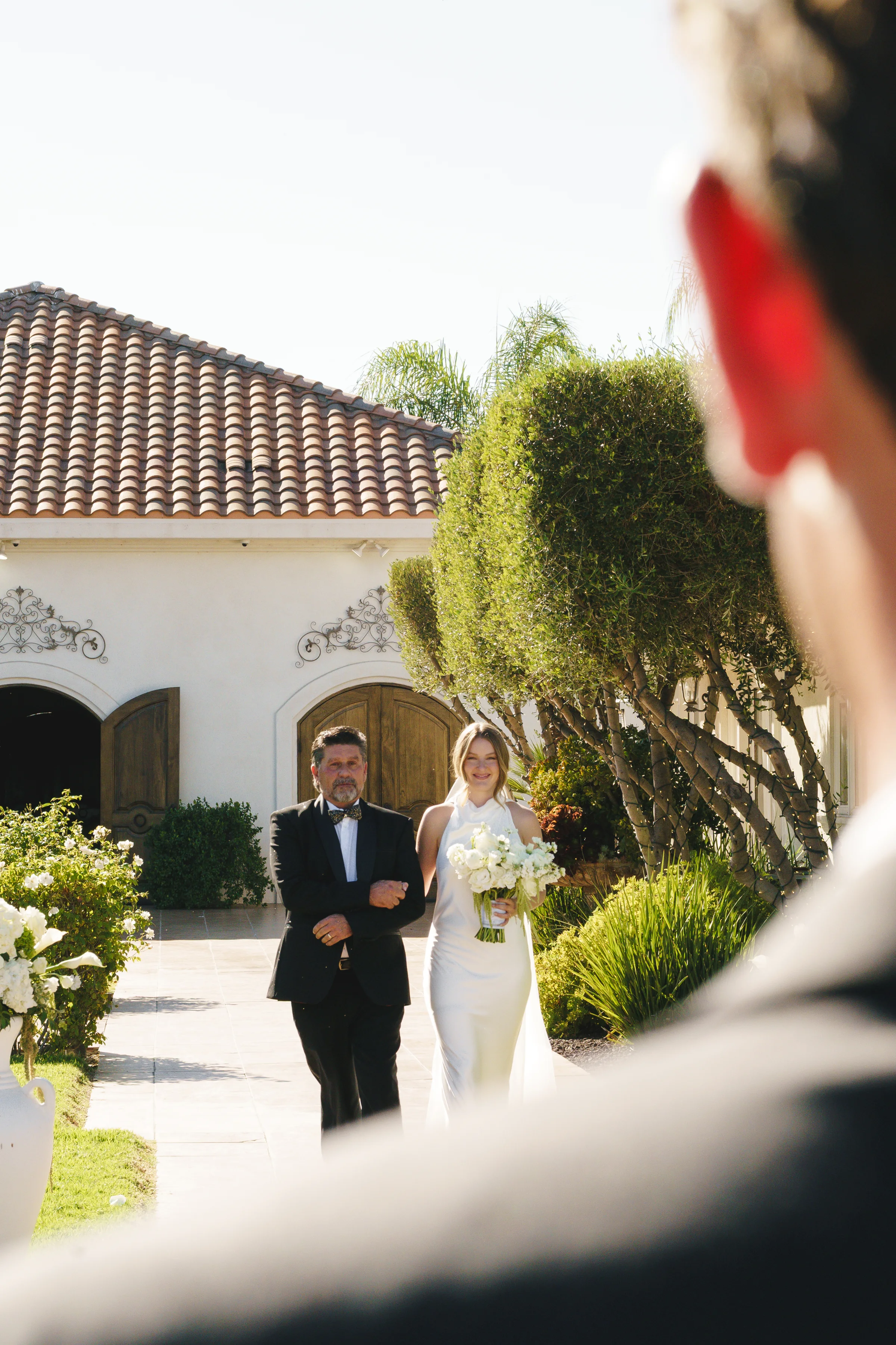 Bride walking toward the outdoor ceremony with her father at Villa de Amore