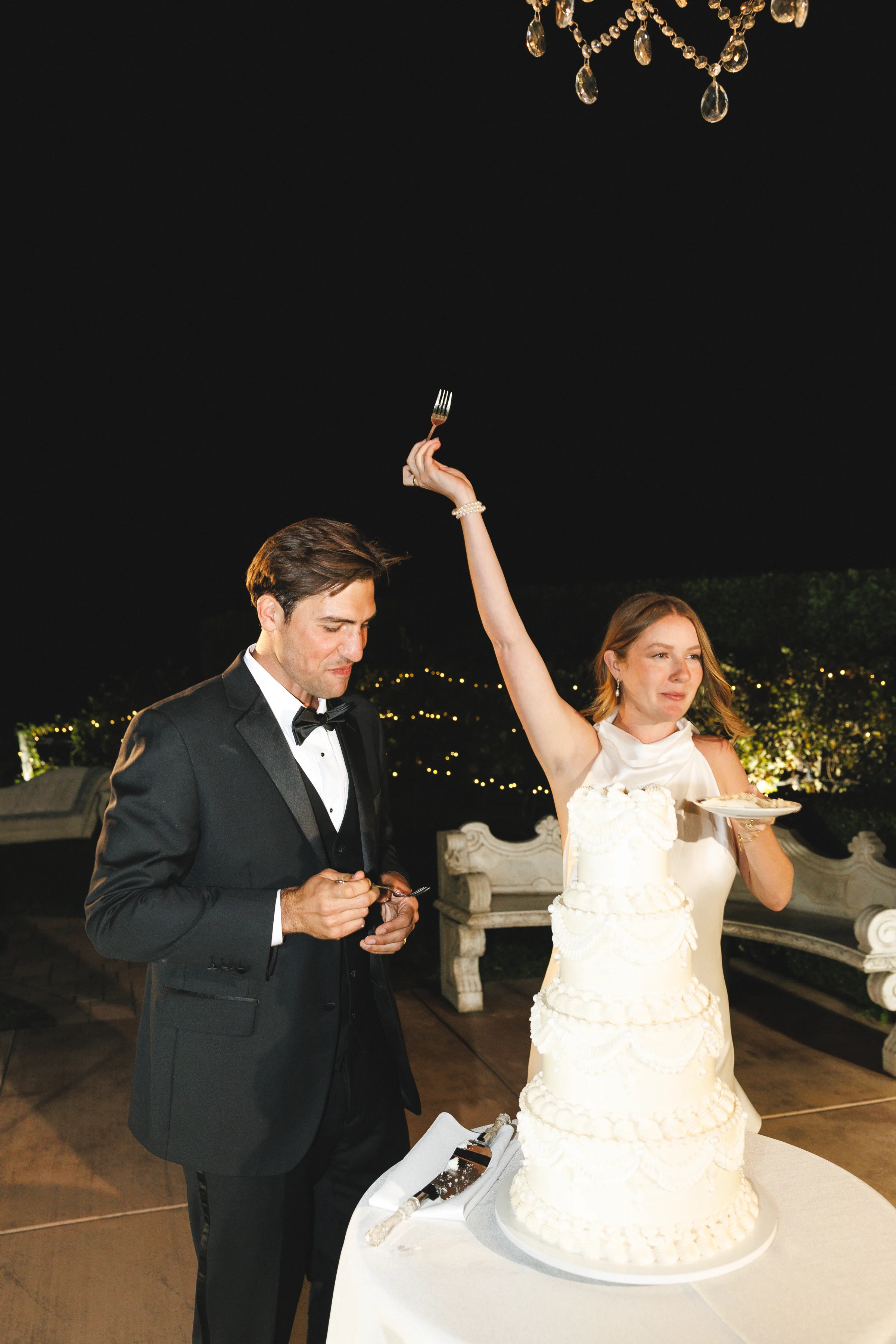 Newlyweds raising their hands after cutting the wedding cake